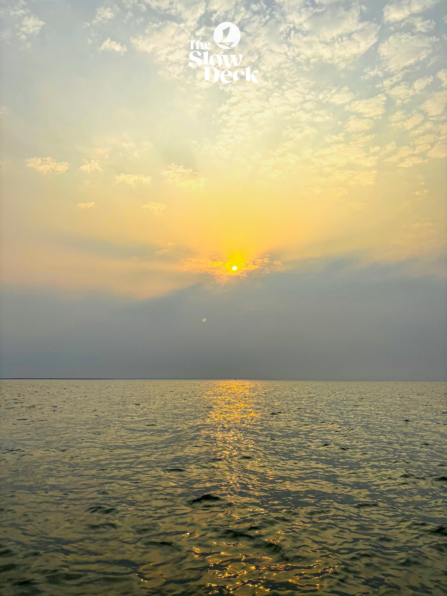 Sunset over the Padma — warm light on the water and shore at the Slow Deck River Retreat.